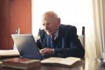 A businessman is looking at his computer while seated at a desk